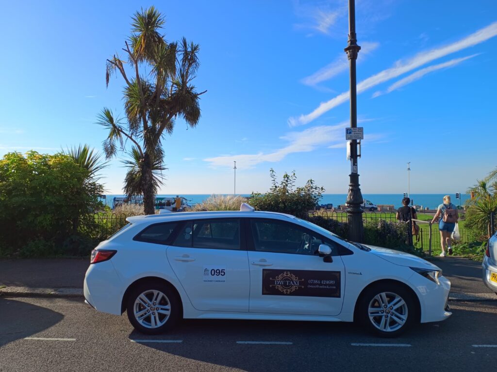 White DW Taxi estate car parked by the seafront